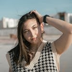 Portrait of a young woman in a stylish houndstooth sweater, enjoying a sunny day outdoors.